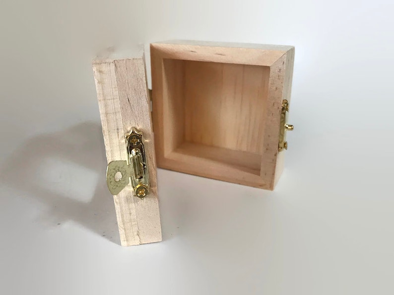 May include: A small wooden box with a hinged lid and a brass latch. The box is open and the inside is empty.