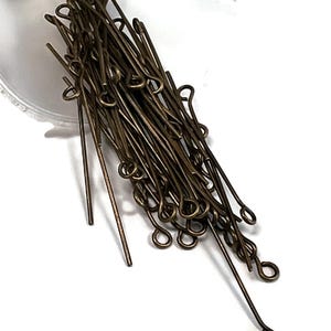 Può includere: Un mucchio di spilli per la testa dorati con anelli. Gli spilli per la testa misurano circa 2,5 cm di lunghezza.