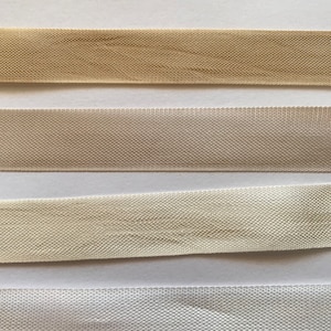 May include: Four samples of beige, cream, and white fabric with a woven texture. The fabric is arranged in rows from darkest to lightest.