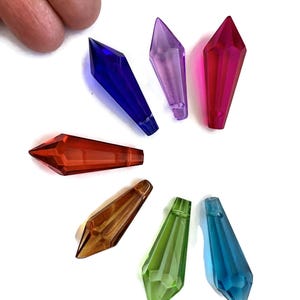 May include: Seven crystal prism pendants in various colors, including red, blue, green, purple, and orange. The prisms are shaped like long, pointed teardrops.