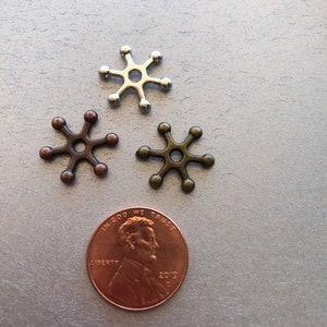 May include: Three metal star-shaped charms, one silver, one bronze, and one copper, with a penny for scale.