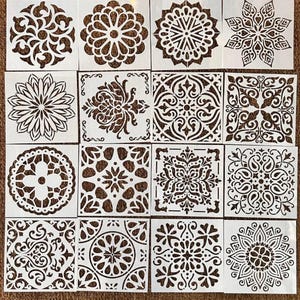 May include: A collection of sixteen square white stencils arranged in a four-by-four grid. Each stencil features a unique, intricate cutout pattern, including various floral, geometric, mandala, and symmetrical scrollwork designs.
