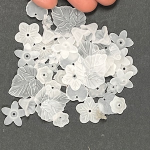 May include: A collection of white plastic flower and leaf shapes. The shapes are translucent and have a slightly textured surface.