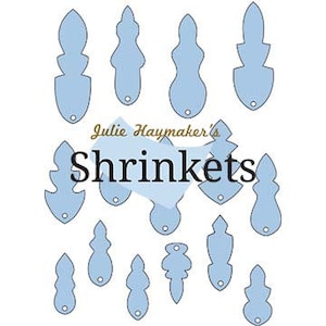 May include: A set of 15 blue shrink plastic shapes with a hole punched in the top. The shapes are various abstract designs. The text "Julie Haymaker's Shrinkets" is printed in black on a white background.