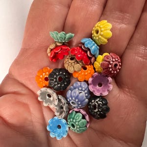 Pu&ograve; includere: Assortimento di perline di ceramica colorate a forma di fiore. Le perline hanno una variet&agrave; di colori, tra cui rosso, arancione, giallo, verde, blu, viola e nero. Le perline hanno un diametro di circa 2,5 cm.