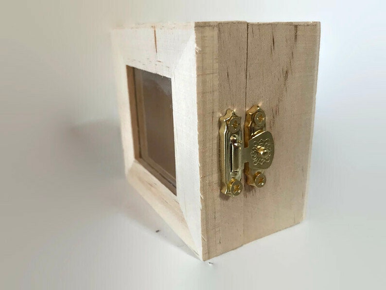 May include: A small wooden box with a clear glass window and a gold latch. The box is painted white and has a distressed finish.