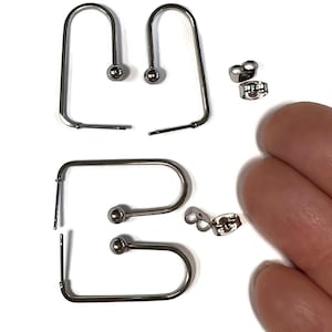 May include: A pair of silver hoop earrings with a small ball at the end of each hoop. The earrings are shown with two sets of earring backs.