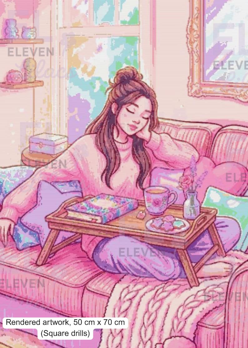 May include: A diamond painting kit featuring a pixelated illustration of a person relaxing on a pink sofa with a wooden breakfast tray holding a book, a floral mug, and cookies. The artwork measures 50 cm by 70 cm and uses square drills.
