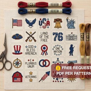 Op de afbeelding: Een kruissteekpatroon op crèmekleurige stof met een raster van patriottische Amerikaanse iconen en teksten zoals USA, Land of the Free, 76, God Bless America, One Nation, E Pluribus Unum, Veterans en July 4th, vergezeld van borduurgaren en een schaar.