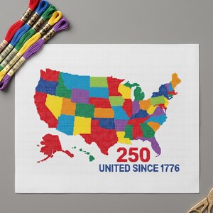 May include: A white needlepoint canvas featuring a multicolored map of the United States, the red text 250, and the blue text UNITED SINCE 1776. Included are five skeins of embroidery floss in red, blue, green, yellow, and purple, and gold scissors.