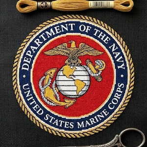 Könnte beinhalten: Ein Kreuzstichprojekt auf schwarzem Stoff mit dem Emblem des United States Marine Corps in Rot, Weiß, Blau und Gold. Darüber liegen drei Stickgarnstränge in Marineblau, Rot und Gold. Darunter befindet sich eine silberne Schere.