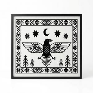 Puede incluir: Un diseño de punto de cruz en blanco y negro enmarcado con un cuervo con las alas extendidas, estrellas, una luna creciente y árboles estilizados. La obra de arte está enmarcada en un marco cuadrado negro.