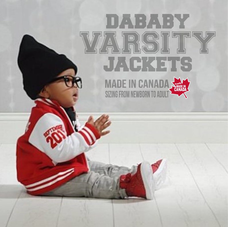 May include: A baby wearing a red and white varsity jacket with the text "SEPTEMBER 201" on the sleeve. The jacket is paired with gray pants and red shoes. The image also includes the text "DABABY VARSITY JACKETS MADE IN CANADA SIZING FROM NEWBORN TO ADULT".