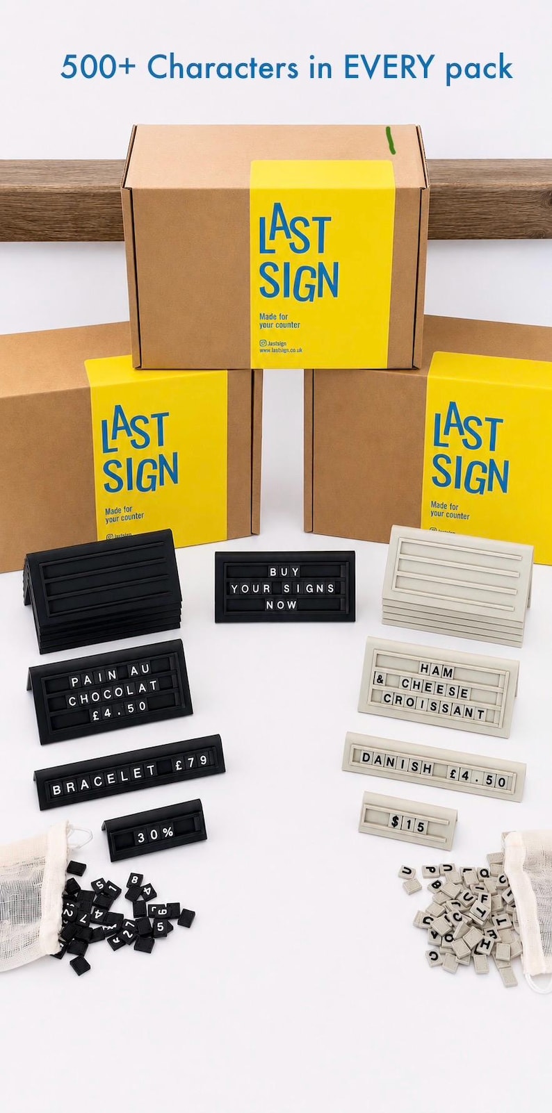 May include: Three brown cardboard boxes with yellow labels reading LAST SIGN, featuring black and beige plastic sign holders with horizontal grooves. Included are small black and beige tiles with letters and numbers, and signs displaying text like PAIN AU CHOCOLAT &pound;4.50, HAM & CHEESE CROISSANT, BRACELET &pound;79, 30%, and $15.