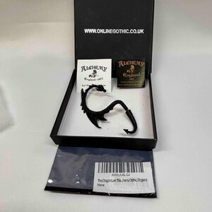 May include: A black dragon-shaped ear cuff in a black presentation box. The box lid features the text WWW.ONLINEGOTHIC.CO.UK. Inside are two small cards with the Alchemy England logo and text, and a barcode label reading The Dragon Lure.