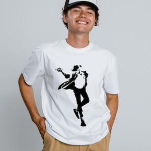 Pode incluir: Camiseta branca com uma silhueta preta de uma figura dançando com chapéu e jaqueta. A pessoa está usando um boné de caminhoneiro branco e preto e calças cáqui. A imagem é definida em um fundo cinza claro.