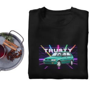May include: Black sweatshirt featuring a teal car graphic with the word "TRUSTY" in a neon font. The design includes a retro grid background with neon lines in pink, yellow, and blue. The car has white rims.