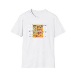 May include: White t-shirt featuring a detailed circuit board design in shades of orange, blue, and green. The graphic includes text labels and symbols, creating a technical aesthetic. A casual, everyday wear tee.