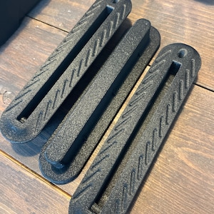 Three matte black 3D-printed Single-Tab fin boxes for Thruster setups, compatible with Futures fin systems, made from carbon fiber reinforced nylon on a wooden background.