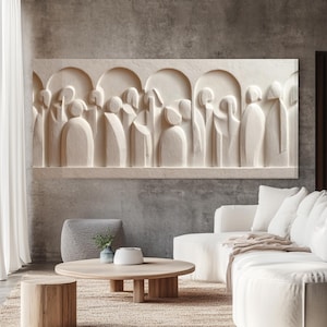 Puede incluir: Una gran escultura en relieve de color blanquecino que representa figuras estilizadas dentro de nichos arqueados. La obra de arte está montada en una pared gris sobre un salón moderno con un sofá blanco, una mesa de centro de madera y una alfombra de tonos neutros.