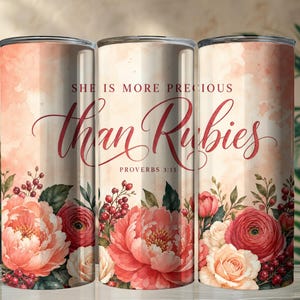 May include: A cylindrical tumbler featuring a watercolor-style peach and cream background with a floral arrangement of pink and red flowers and berries. The text reads "SHE IS MORE PRECIOUS than Rubies PROVERBS 3:15" in a mix of serif and script fonts.