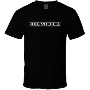 May include: Black t-shirt with the white text "PAUL MITCHELL" in a sans-serif font. The text is centered horizontally and is enclosed by two thin horizontal lines. The shirt has short sleeves and a crew neck.