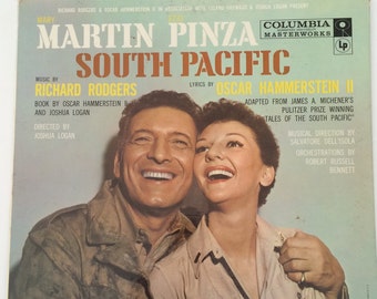 May include: A vintage vinyl record cover featuring a photo of Martin Pinza and a woman, both smiling. The cover is blue and white with the title "South Pacific" and the names "Richard Rodgers" and "Oscar Hammerstein II" in large, bold font. The record is a Columbia Masterworks LP.