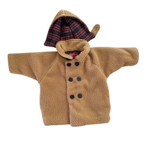 May include: A tan fleece jacket with a matching hood. The jacket has a double-breasted design with four black buttons. The hood is lined with a red, black, and green plaid pattern.