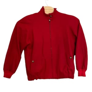 May include: A red zip-up jacket with a high collar and a drawstring at the bottom.