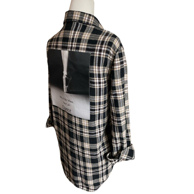 May include: Black and white plaid flannel shirt with a black and white photo patch on the back. The patch features a ballerina's foot and the text "Why Walk When You Can Dance".