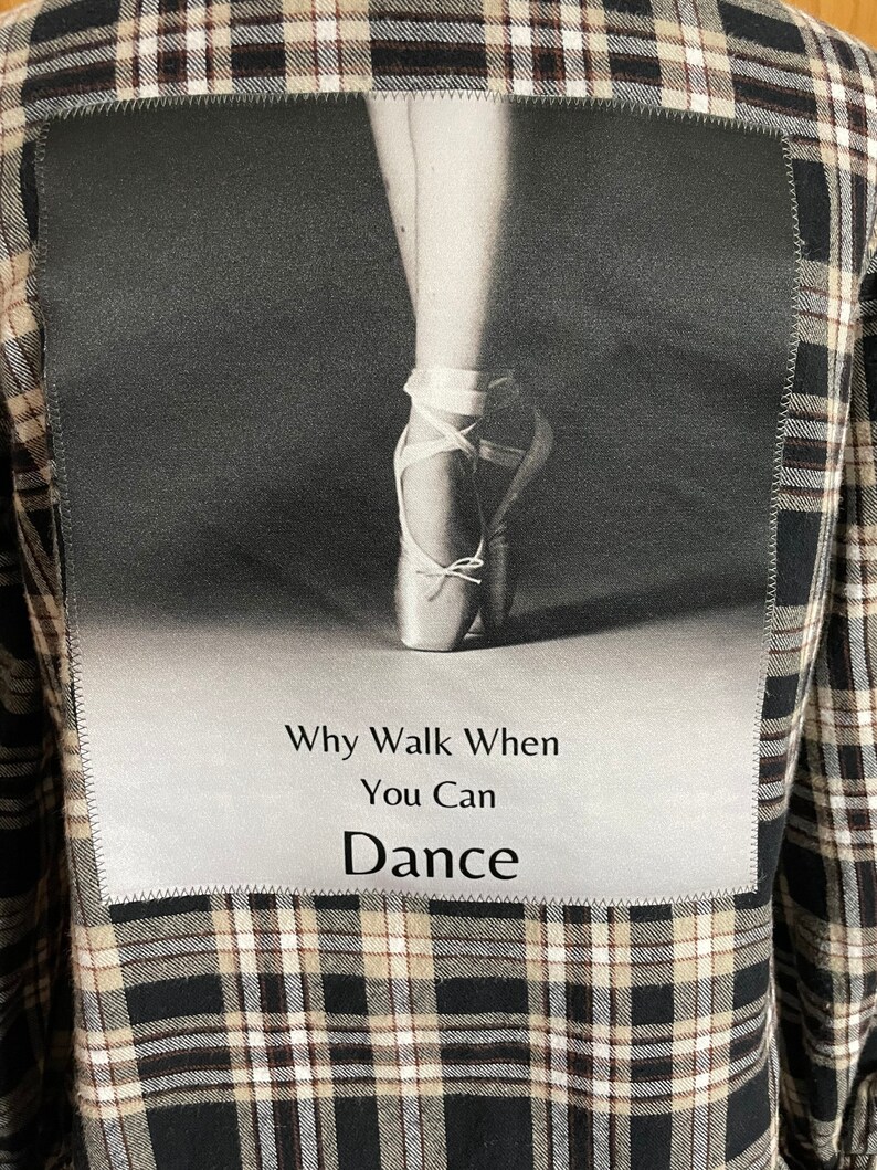 May include: A black and white photo of a ballerina's foot in a pointe shoe. The photo is on a black and white plaid fabric background. The text "Why Walk When You Can Dance" is printed below the photo.