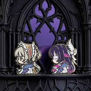 Può includere: Due spille smaltate raffiguranti personaggi in stile anime di profilo. La spilla a sinistra mostra un personaggio con capelli biondi e un copricapo bianco. La spilla a destra mostra un personaggio con capelli viola scuro e un'ala bianca.