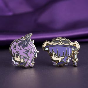 May include: Two enamel pins featuring anime-style characters with purple and gold accents. One pin depicts a character with spiky purple hair and horns, while the other shows a character with a hat and a staff. The pins are set against a purple background.