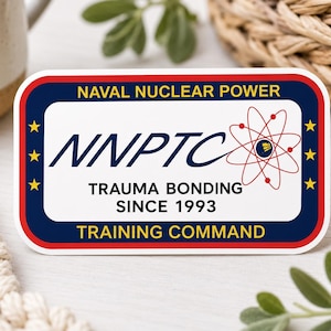 May include: A rectangular sticker with a white center and a dark blue border outlined in red. It features the text NAVAL NUCLEAR POWER, NNPTC, TRAUMA BONDING SINCE 1993, and TRAINING COMMAND, along with a red atomic symbol and three yellow stars on each side.