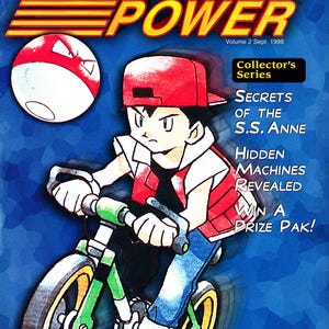 Pode incluir: Capa de banda desenhada Pok&eacute;mon Power, Volume 2, com uma personagem a andar de bicicleta verde e amarela. A capa inclui o texto "Gotta catch 'em all!" e "Collector's Series".