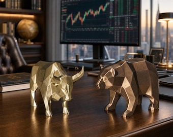 Puede incluir: Una figura geométrica de toro en color dorado y una figura geométrica de oso en color bronce. Ambas estatuas presentan facetas angulares marcadas y un acabado metálico, colocadas una al lado de la otra sobre una superficie de madera oscura.