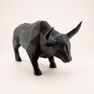 A black faceted bull statue is shown from a slightly elevated angle on a light beige background.