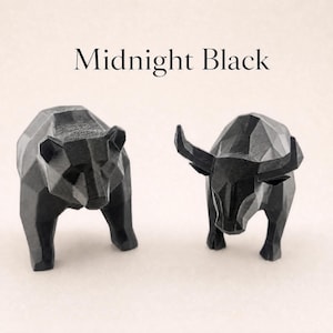 A black geometric bear and a black geometric bull statue stand side-by-side on a light background, with the text "Midnight Black" above them.