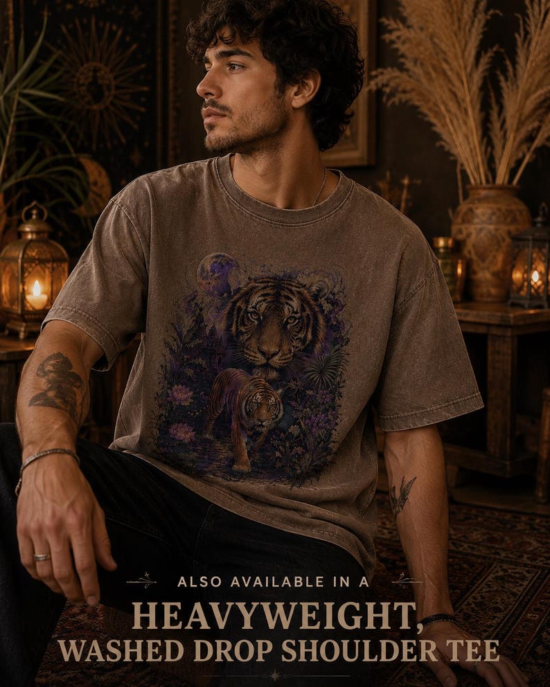 May include: A brown, washed-effect short-sleeve t-shirt featuring a graphic print of two tigers in a jungle setting with a moon. The text at the bottom reads: ALSO AVAILABLE IN A HEAVYWEIGHT, WASHED DROP SHOULDER TEE.