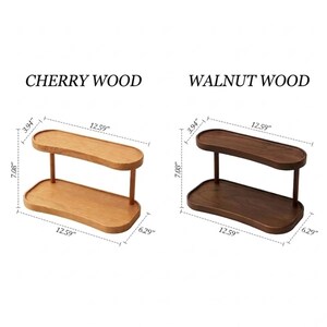 May include: Two-tiered wooden display shelf in cherry and walnut. The cherry wood shelf is light brown, and the walnut wood shelf is dark brown. Each shelf is 12.59 inches long, 6.29 inches wide, and 7.08 inches tall.