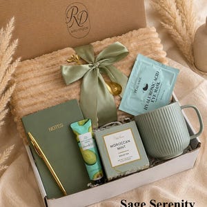 Peut inclure: Un coffret cadeau contenant une couverture c&ocirc;tel&eacute;e beige, un carnet vert sauge marqu&eacute; NOTES, un stylo dor&eacute;, un tube de cr&egrave;me pour les mains &agrave; l'avocat, du th&eacute; vert Moroccan Mint, un masque pour les yeux Peauamie, un mug sauge et un ruban.