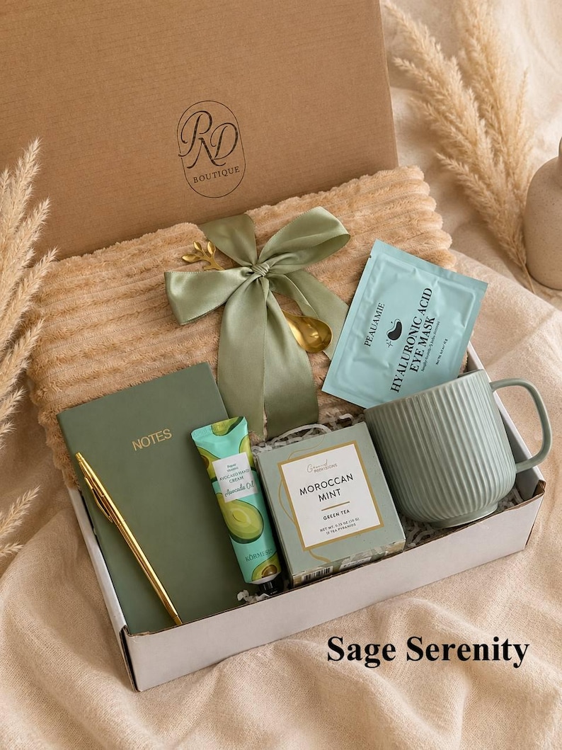 Peut inclure: Un coffret cadeau contenant une couverture c&ocirc;tel&eacute;e beige, un carnet vert sauge marqu&eacute; NOTES, un stylo dor&eacute;, un tube de cr&egrave;me pour les mains &agrave; l'avocat, du th&eacute; vert Moroccan Mint, un masque pour les yeux Peauamie, un mug sauge et un ruban.