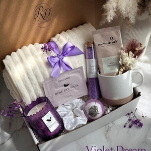 Peut inclure: Coffret cadeau avec une couverture blanche, un ruban violet, une bougie violette, une tasse, des produits de bain et un masque pour les yeux. Le coffret est intitulé "Violet Dream".