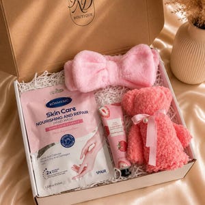 May include: A pink gift box containing a pink headband, a hand mask, a strawberry hand cream, and a pink teddy bear. The box is labeled "RD Boutique" and the text "Pink Bliss" is at the bottom.