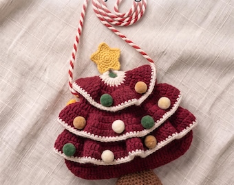 May include: A crochet crossbody bag shaped like a Christmas tree with a red, white, and green color scheme, featuring a yellow star topper, small pom-poms, and a brown base. The text reads: Crochet Christmas Tree Crossbody Bag Pattern Instant PDF Download.