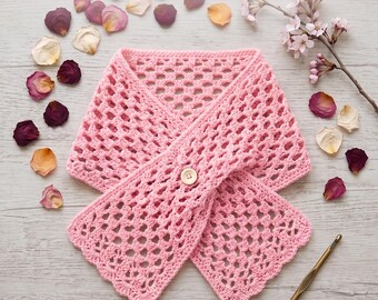 Könnte beinhalten: Ein hellrosa gehäkelter Kragen mit einem durchbrochenen Muster und einem einzelnen Knopf in der Mitte. Der Text lautet Vintage Rose Button Cowl Crochet Pattern und Instant PDF Download. Eine goldene Häkelnadel liegt unten rechts.