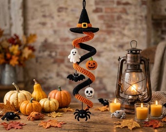 May include: A hanging crochet spiral decoration featuring a black witch hat at the top, alternating orange and black coils, and dangling amigurumi figures including a white ghost, orange pumpkin, black bat, white skull, and black spider.
