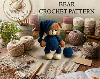 May include: A crochet pattern titled THE SLEEPY PAJAMA BEAR CROCHET PATTERN featuring a brown bear plush wearing a dark blue nightcap and pajamas, surrounded by various yarn balls, a ceramic mug with crochet hooks, and an open instruction book.