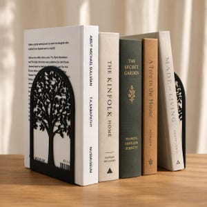 Puede incluir: Libros sujetos por sujetalibros de metal negro con forma de árbol. Los libros son de varios colores, con títulos como "The Secret Garden" y "Made for Living". Los sujetalibros añaden un toque elegante a cualquier estantería.