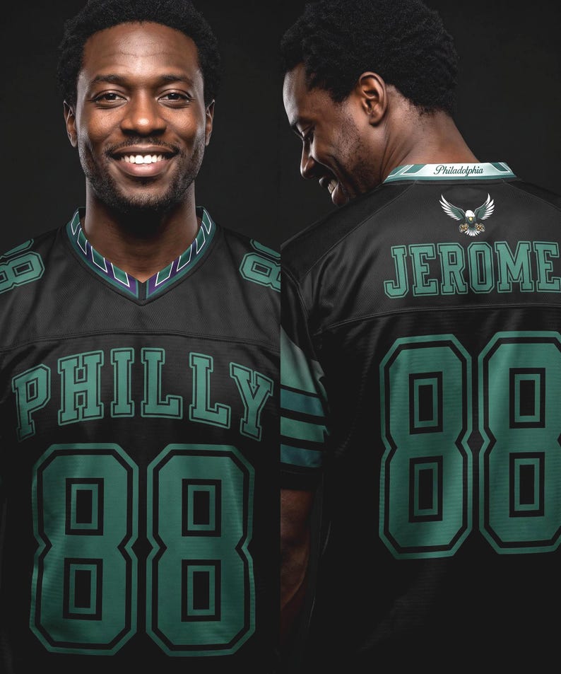 May include: A black sports jersey featuring the word PHILLY and the number 88 in teal with black outlines on the front. The back displays the name JEROME, the number 88, an eagle graphic, and the word Philadelphia on the collar in teal and white.